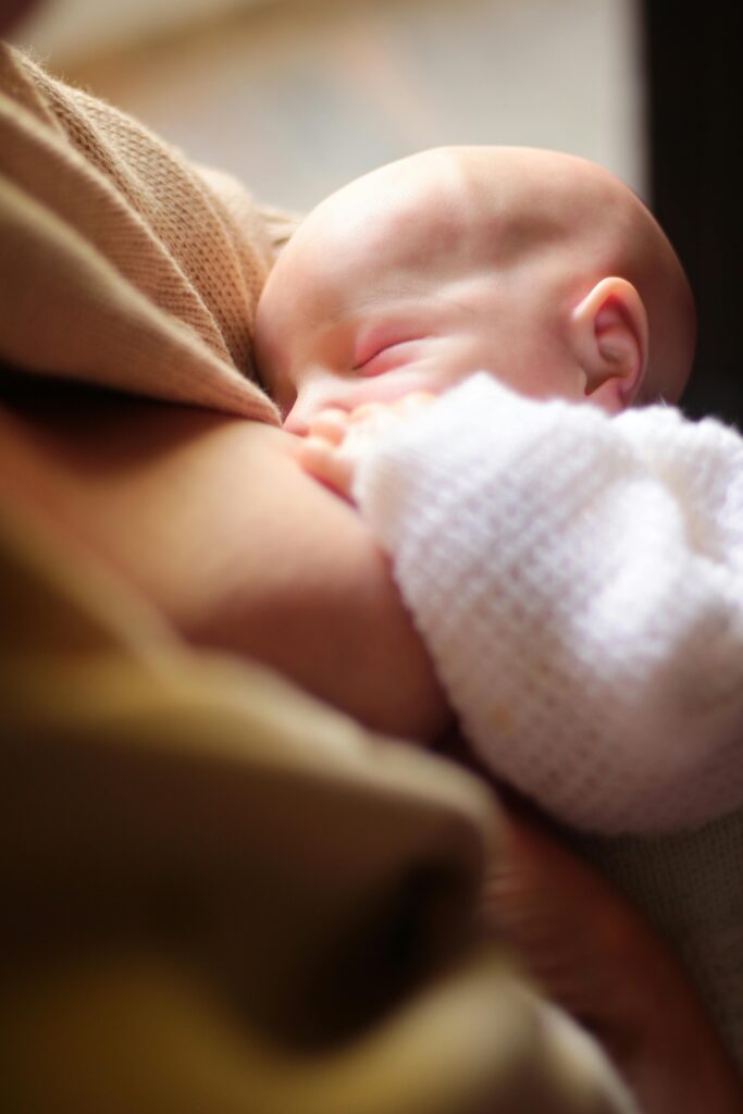 A tender moment of a mother breastfeeding her baby in soft natural light.